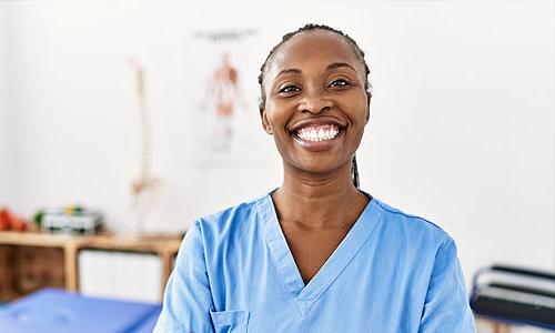 Physical therapy student in scrubs smiling in clinic